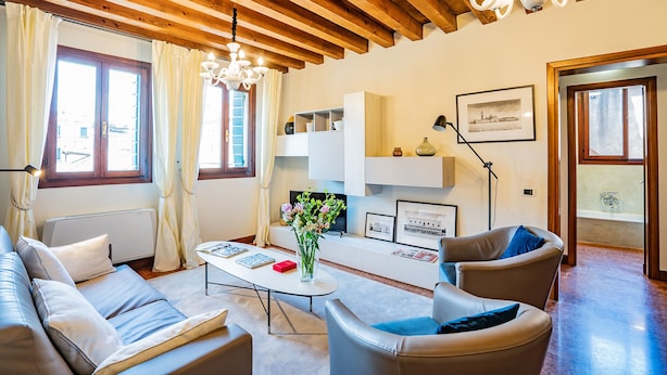 Ein Wohnzimmer mit Holzboden, einem weißen Sofa, einem Couchtisch und einer Pendelleuchte.