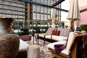 Un área de estar exterior acogedora con un sofá, una mesa y un jarrón decorativo.