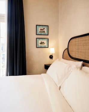 Habitació d'hotel amb un llit, una taula de nit amb una làmpada i dues imatges emmarcades a la paret.