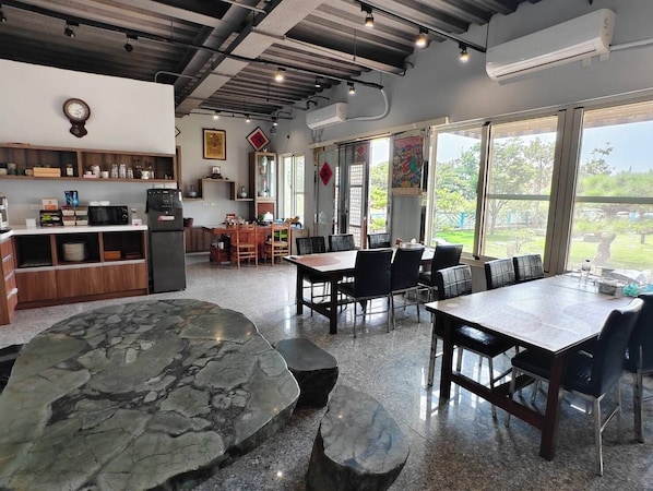 A modern kitchen with a dining area, large windows, and a view of the outdoors.