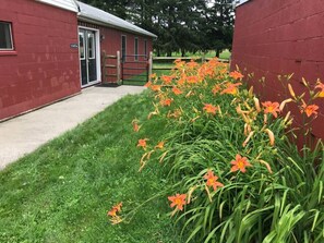 Un edificio rojo con una puerta y un pequeño jardín con flores anaranjadas.