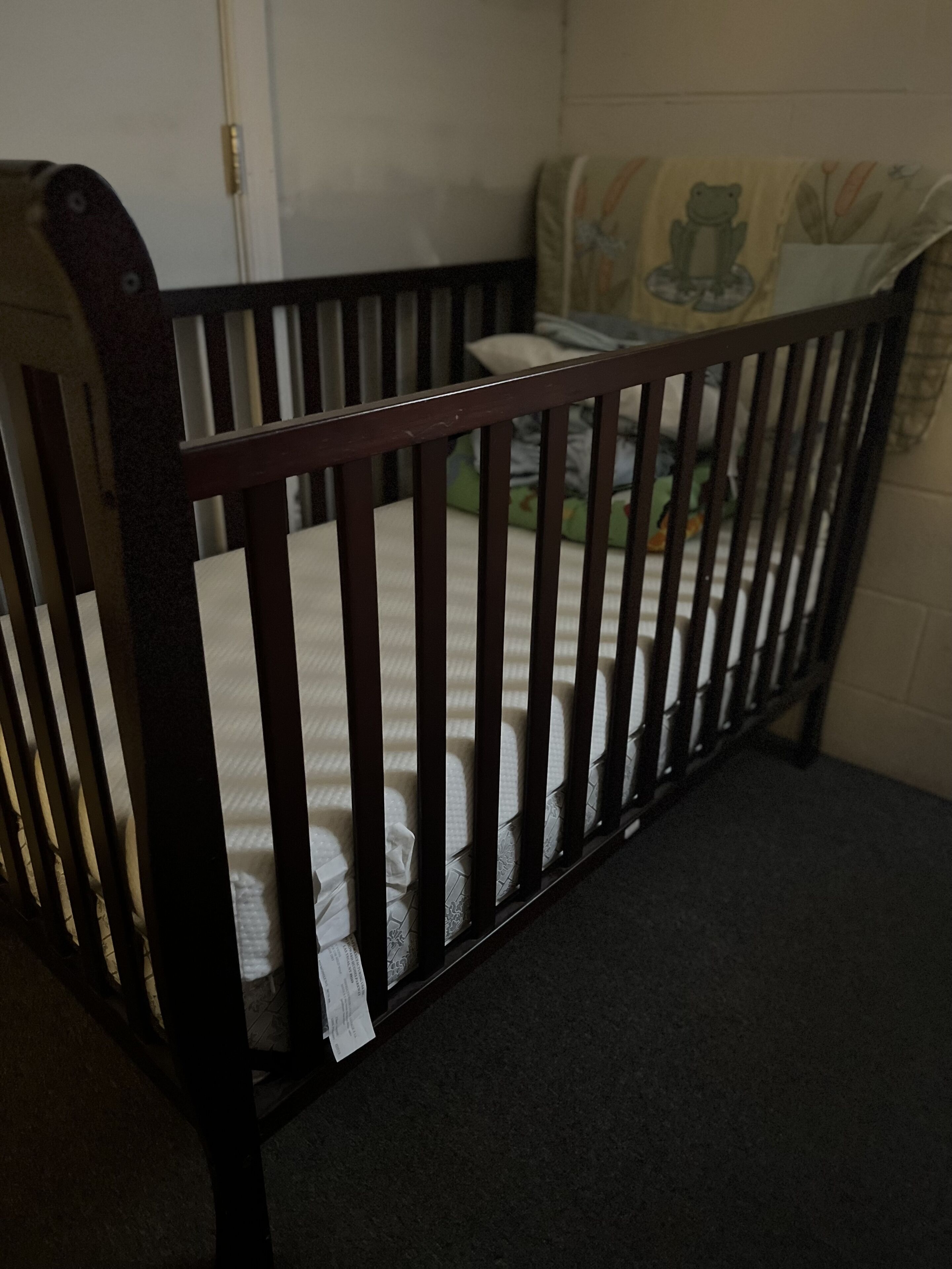 Una cuna de madera con colchón y almohada.