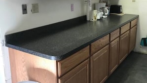 Una cocina con gabinetes de madera, encimera negra y cafetera.