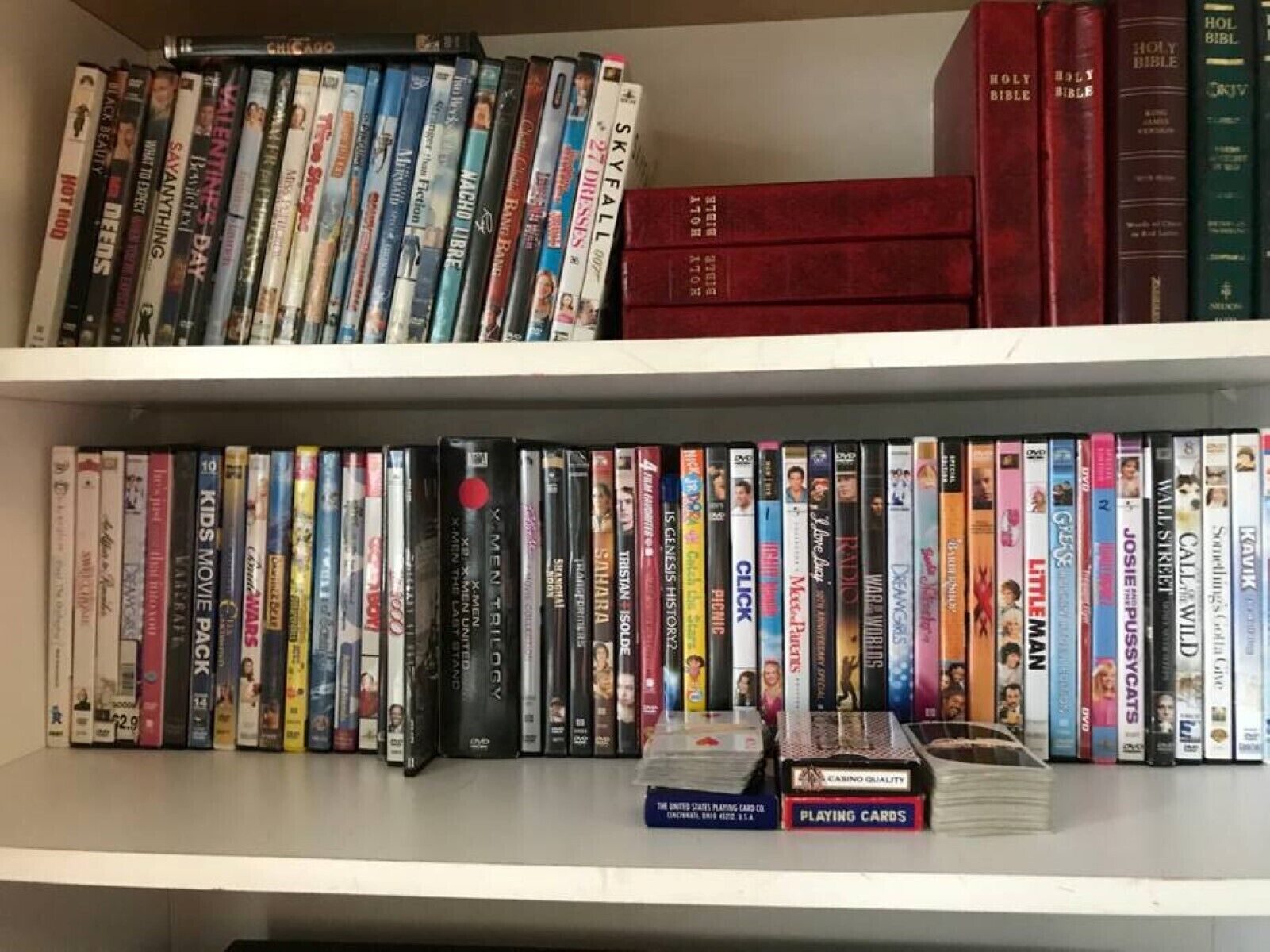 Een boekenplank met verschillende dvd's en boeken, waaronder religieuze teksten en kaarten.