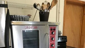 Una cocina con un refrigerador de acero inoxidable, horno empotrado y microondas.