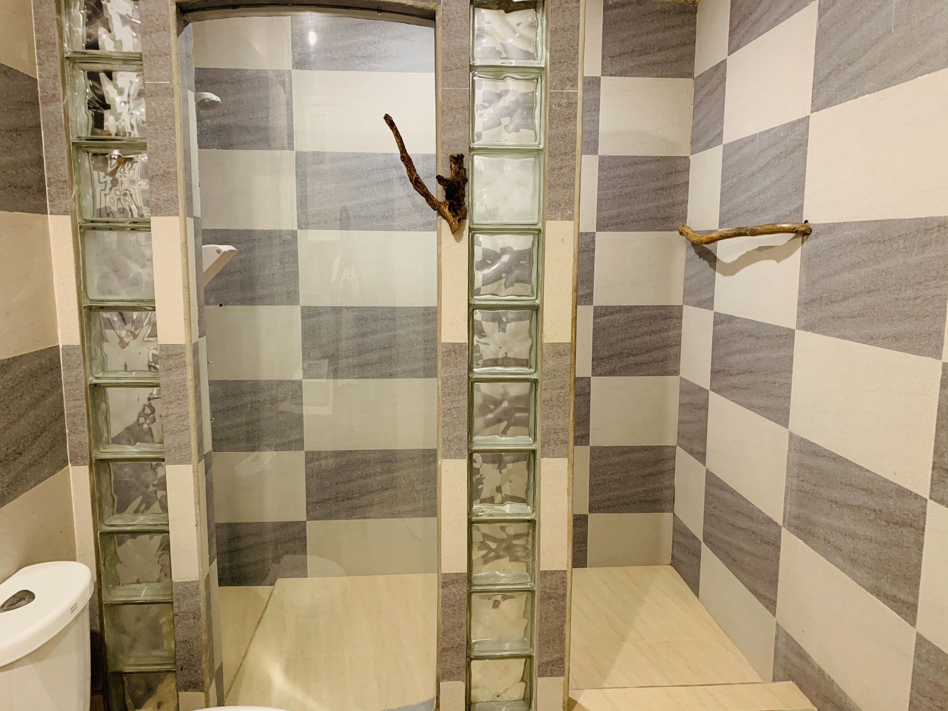 A bathroom with a checkered tile pattern, a glass shower enclosure, and a wooden towel rack.
