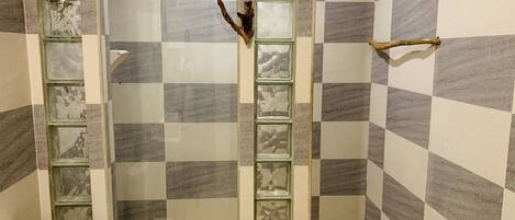 A bathroom with a checkered tile pattern, a glass shower enclosure, and a wooden towel rack.