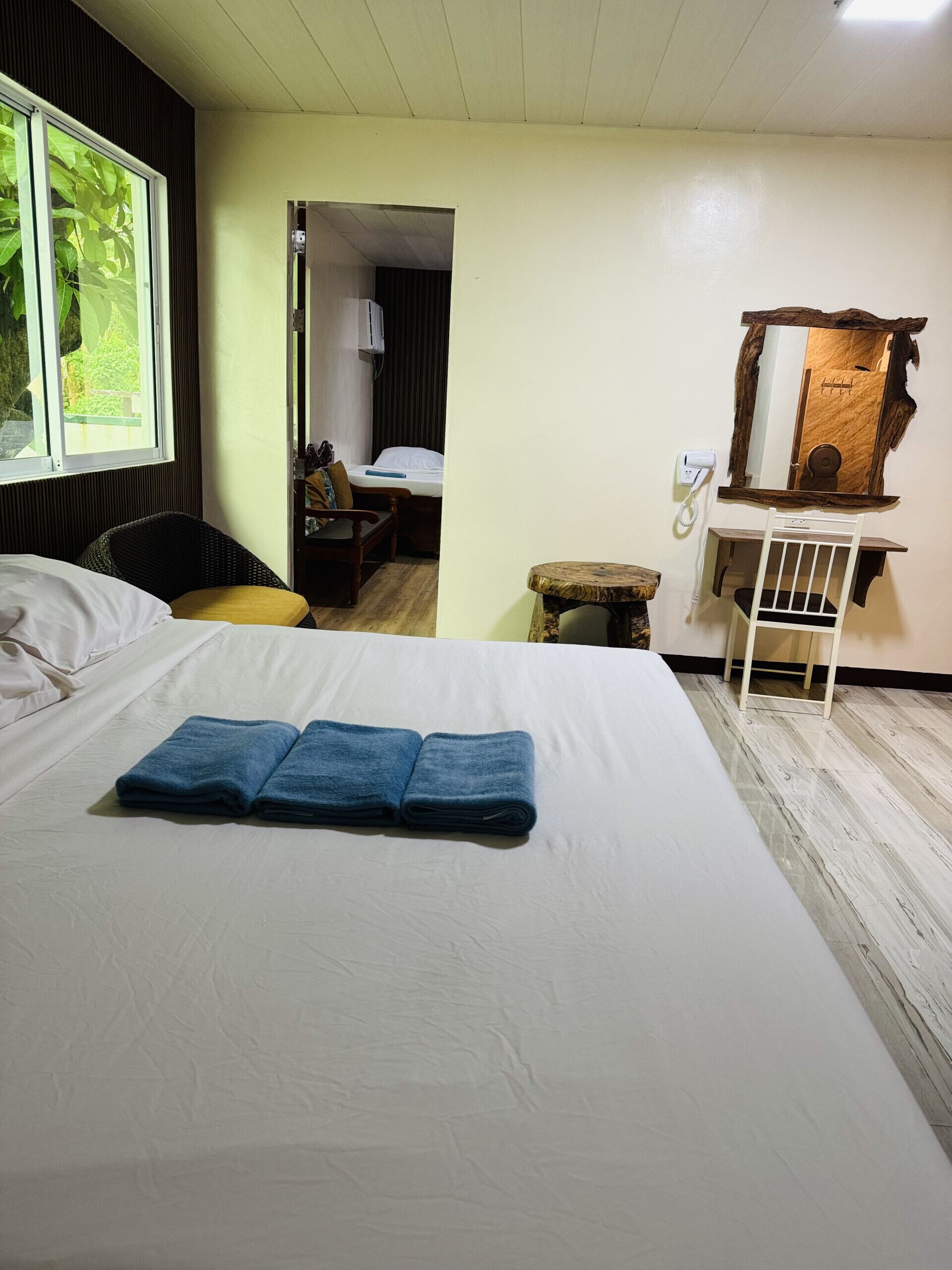 A hotel room with a bed, a desk, a chair, and a mirror.
