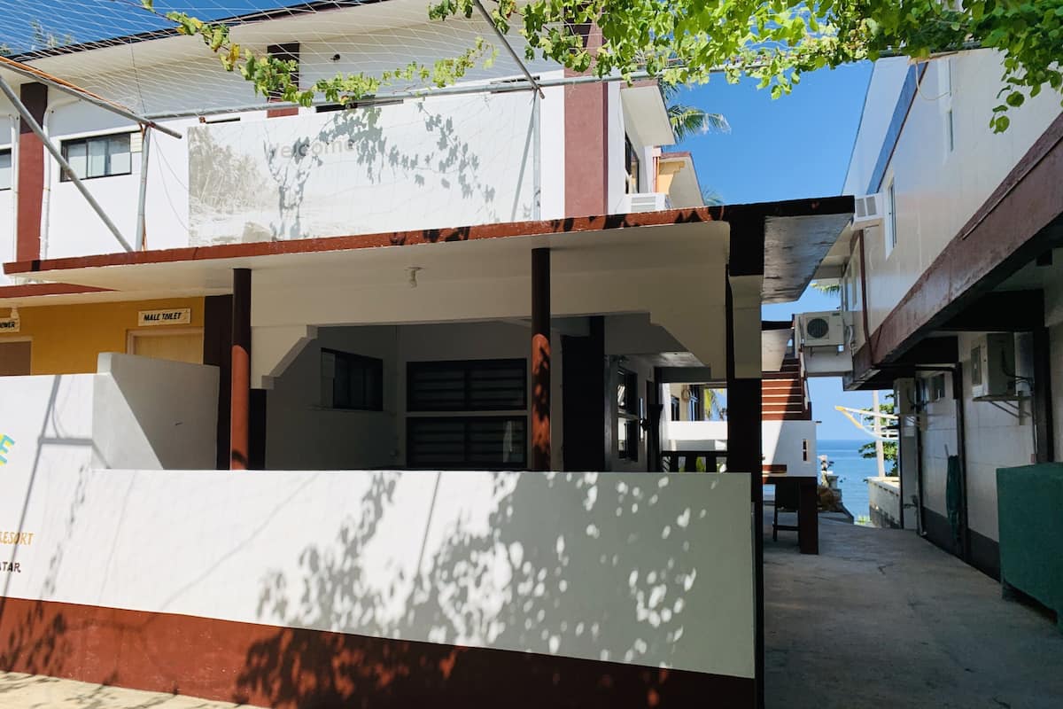 Ein Gebäude mit weißer Fassade, einem sichtbaren Herrentoiletten-Schild und Blick aufs Meer.