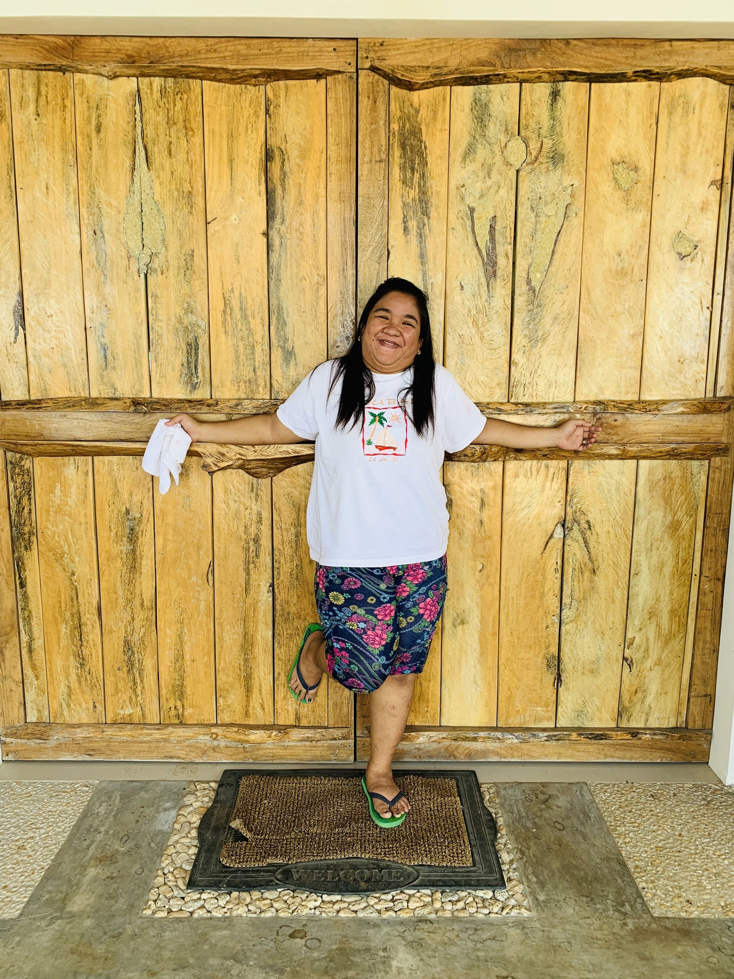 A person standing in front of a wooden door with a welcome mat.