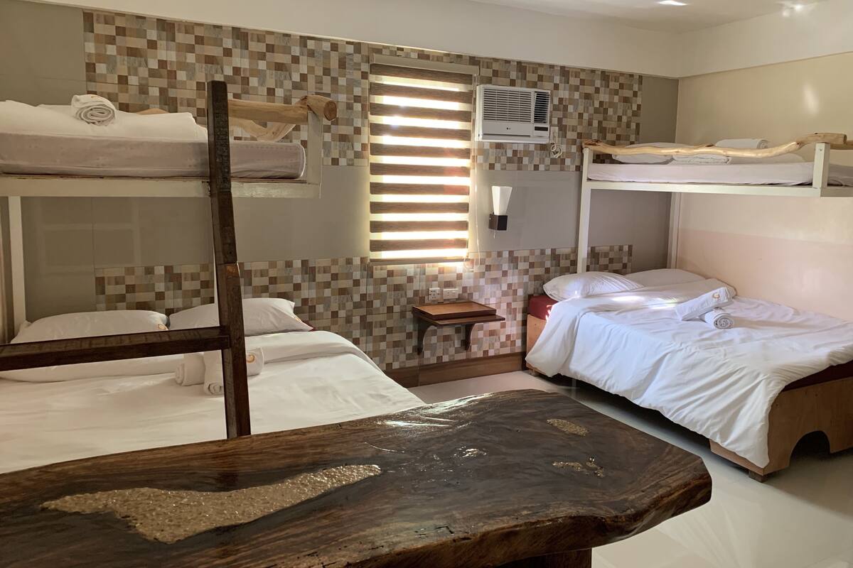 Ein Zimmer mit Etagenbetten, einem Holztisch und einer gefliesten Wand.