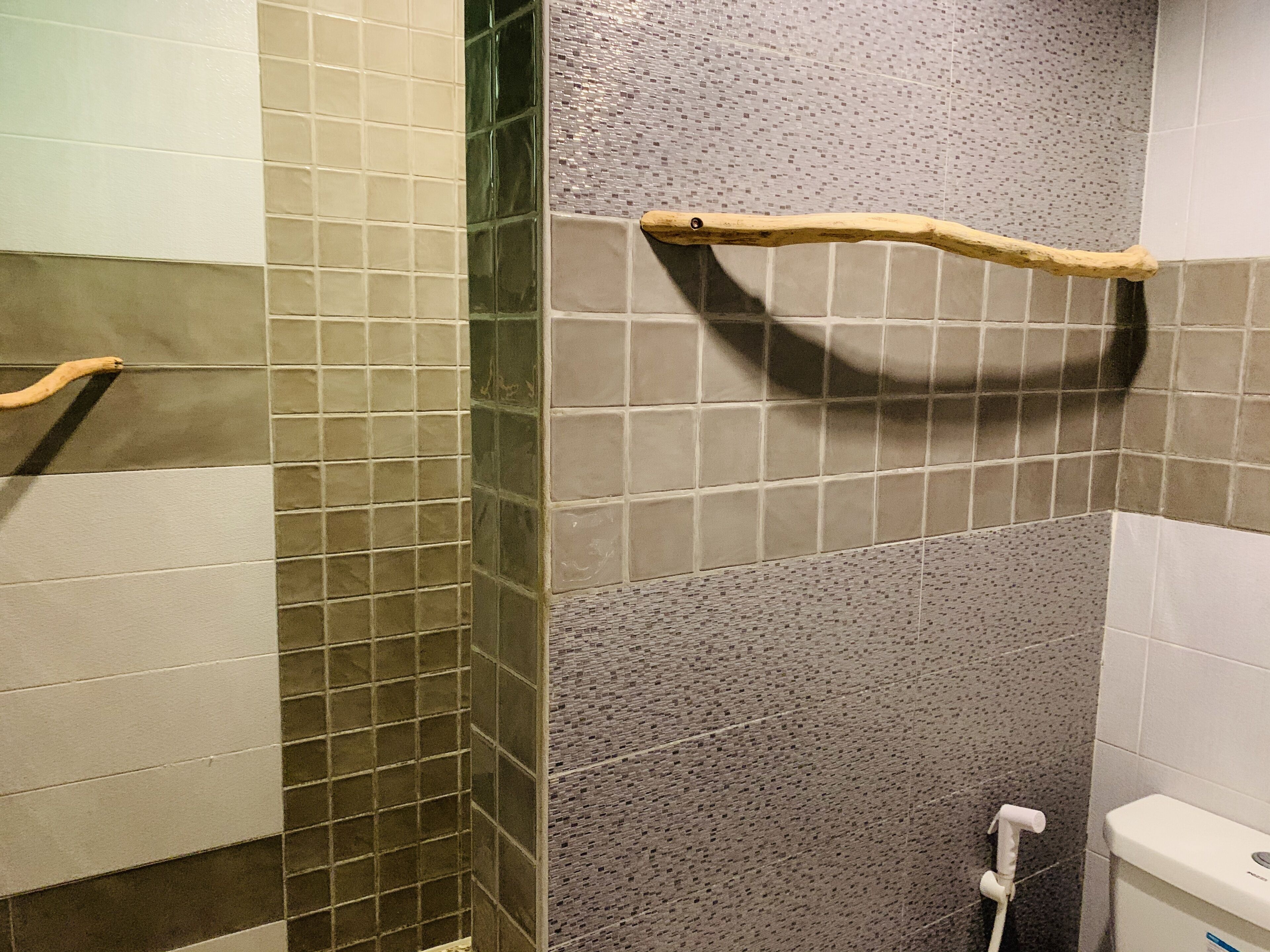 A bathroom with a tiled wall, a wooden towel rack, and a toilet.