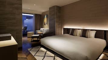 Habitación de hotel moderna con una cama grande, una zona de estar con una mesita y vistas al exterior.