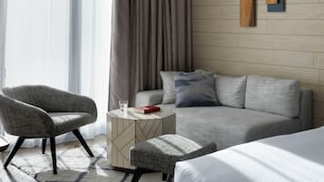 Quarto de hotel moderno com sofá, poltrona, banqueta e cama.
