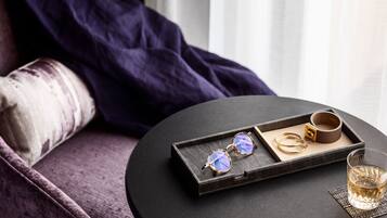 A room with a round table, a pair of glasses, a cup, and a glass of liquid.