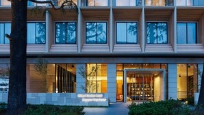 Een meerlaags hotel met een modern architectonisch ontwerp, met grote ramen en een goed verlichte entree.