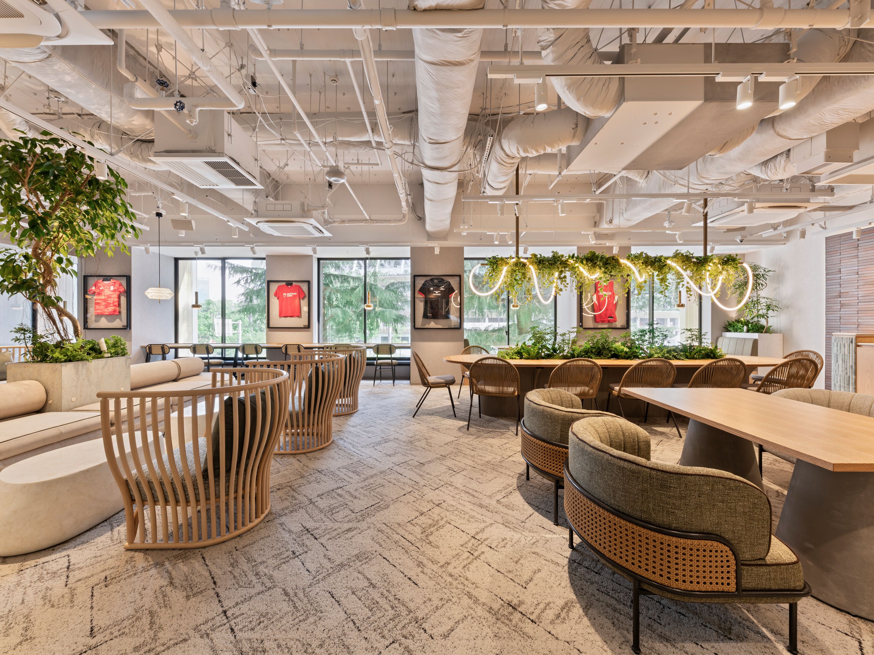 A modern interior with exposed ceilings, seating arrangements, and large windows.