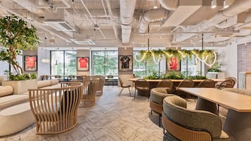 A modern interior with exposed ceilings, seating arrangements, and large windows.