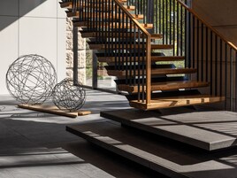 A modern staircase with wooden steps and black railings, leading to an upper level.