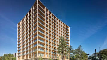 A modern multi-story building with a grid-like facade, large windows, and a flat roof.