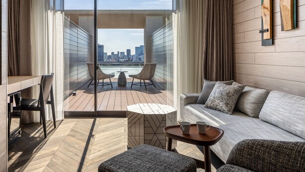 Een moderne hotelkamer met balkon, een bank, een tafeltje en een stoel.