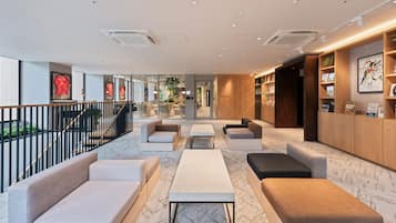 Un área de estar moderna con asientos, una recepción y vistas al exterior.