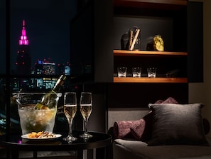 Zona de bar con vista al horizonte urbano, una botella de champán, copas y un plato de frutos secos.