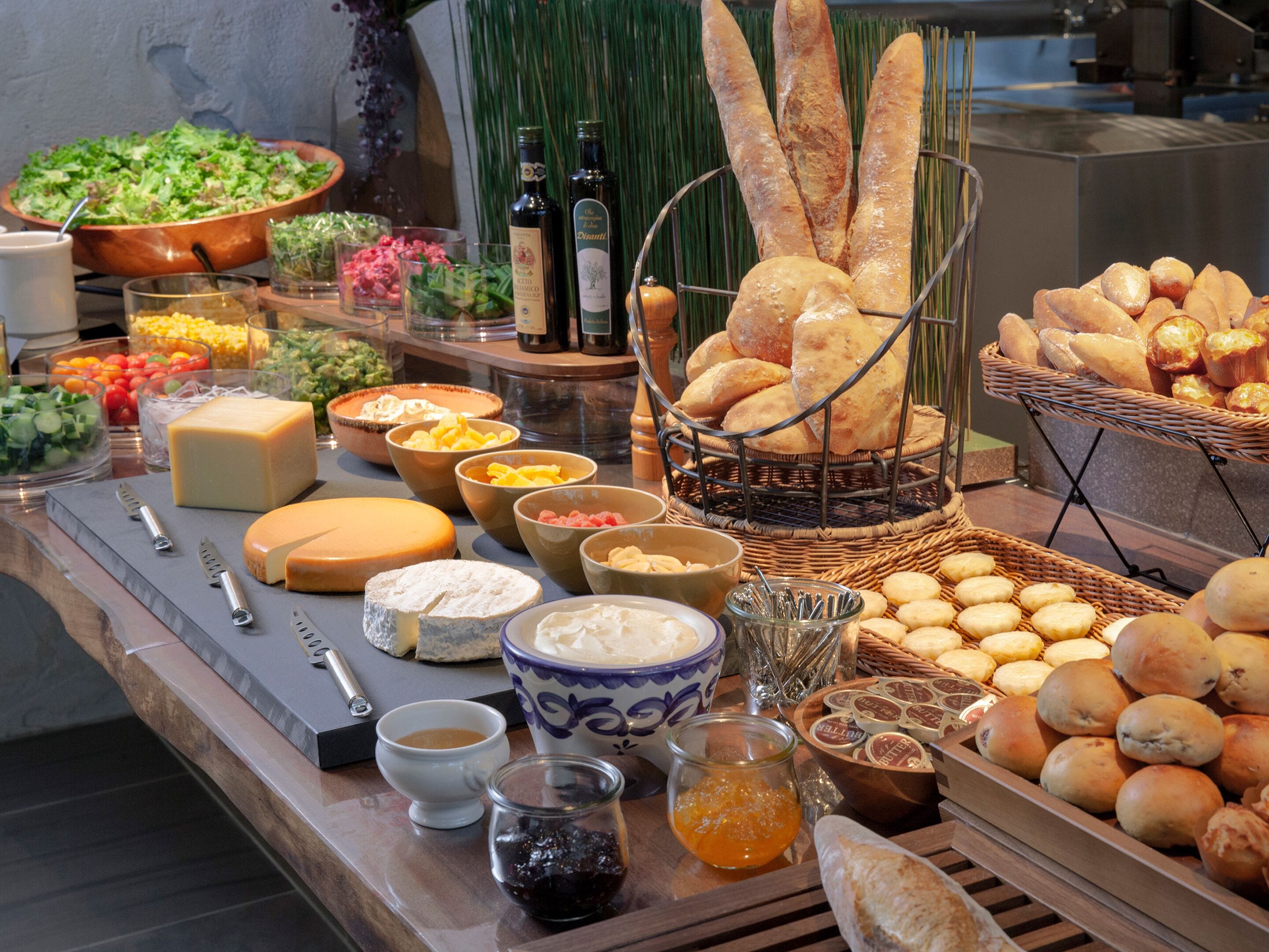 A buffet with various cheeses, breads, and condiments.
