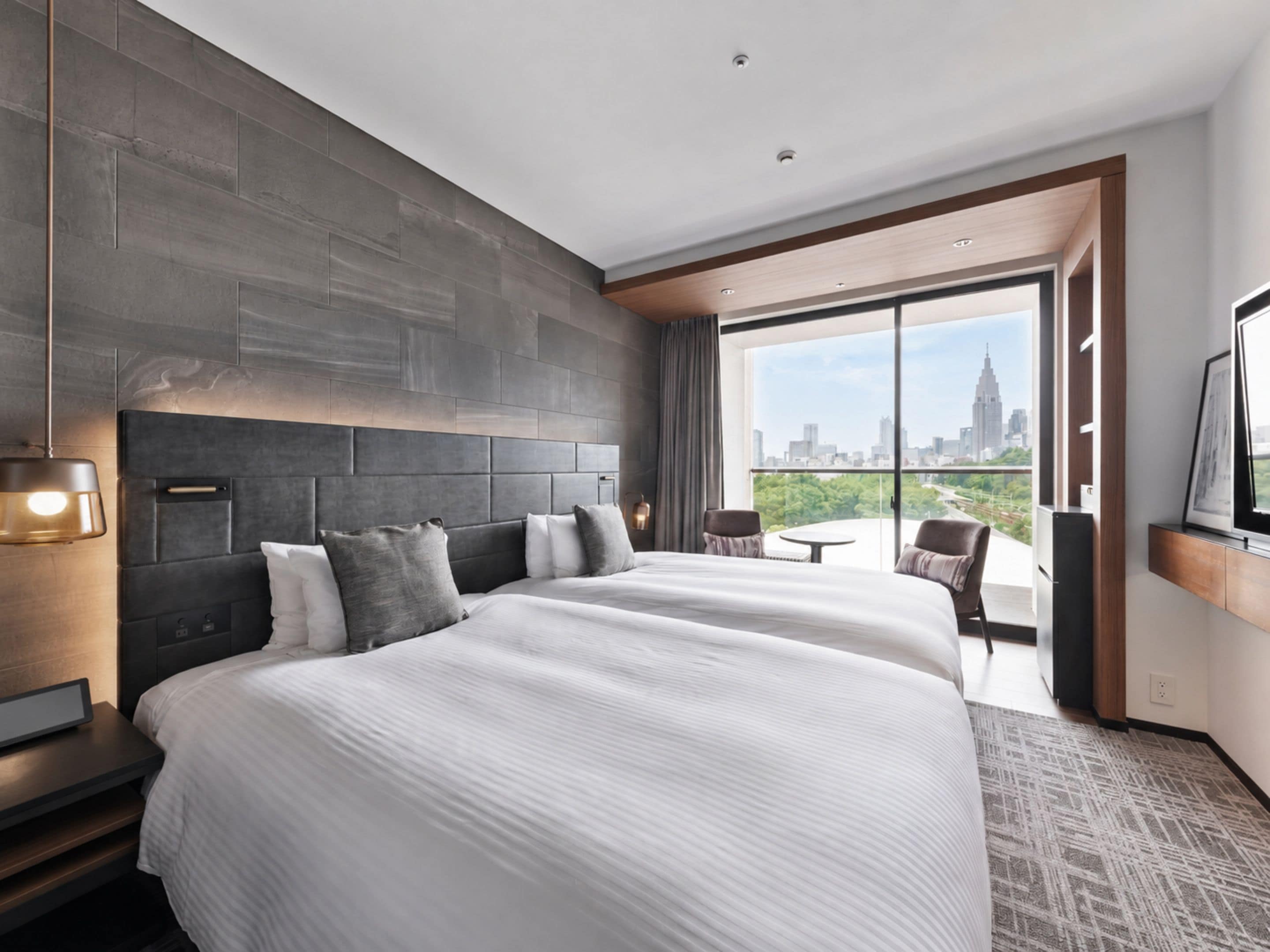A modern hotel room with a large bed, a city view, and a balcony.