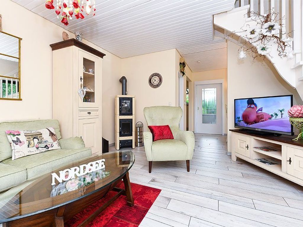 A living room with a sofa, armchair, TV, and a fireplace.