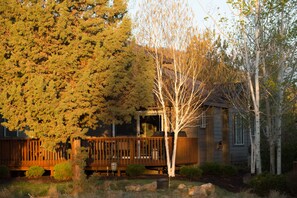 A house with a wooden deck, surrounded by trees and a well-maintained garden.