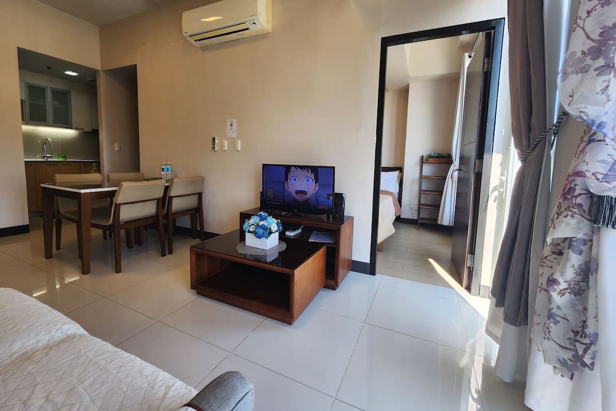 A hotel room with a dining area, kitchenette, TV, and a bed.