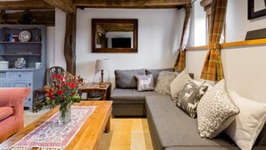 Una sala de estar acogedora con un sofá, una mesa de centro de madera y un jarrón de flores.