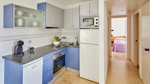 Una cocina compacta con armarios azules, horno empotrado, microondas y lavavajillas.