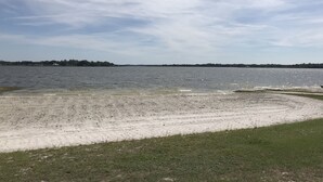 Una playa con orilla arenosa y una zona cubierta de césped al frente.