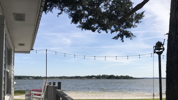 Un muelle de madera con barandilla que da a un lago, una guirnalda de luces y un farol.