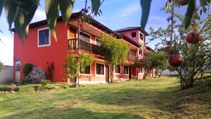 A two-story building with a red facade and a balcony. - Hostería El Tisaleño (Tizaleo)