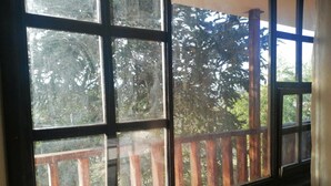 A window with a view of a wooden deck and trees. - Hostería El Tisaleño (Tizaleo)