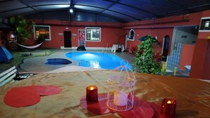 A covered outdoor area with a pool, a table with candles, and a hammock. - Hostería El Tisaleño (Tizaleo)