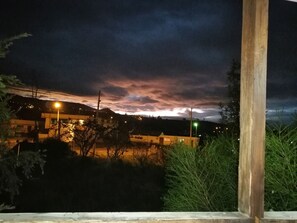 Vista nocturna de una zona residencial con casas, farolas y cielo nublado.