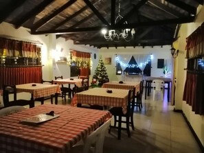 Un restaurante con manteles a cuadros, sillas de madera y una araña.