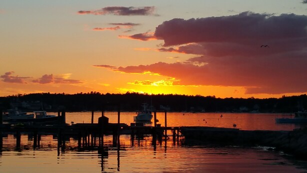 A sunset over a calm body of water with boats docked at a pier. - Gorgeous Views of Harbor Entrance! Walk to town, east side location. (Boothbay Harbor)