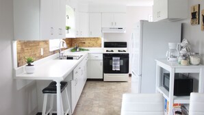 A modern kitchen with white cabinets, a wooden backsplash, a built-in oven, and a coffee machine. - Small Home Paradise - close to Lancaster attractions (Paradise)