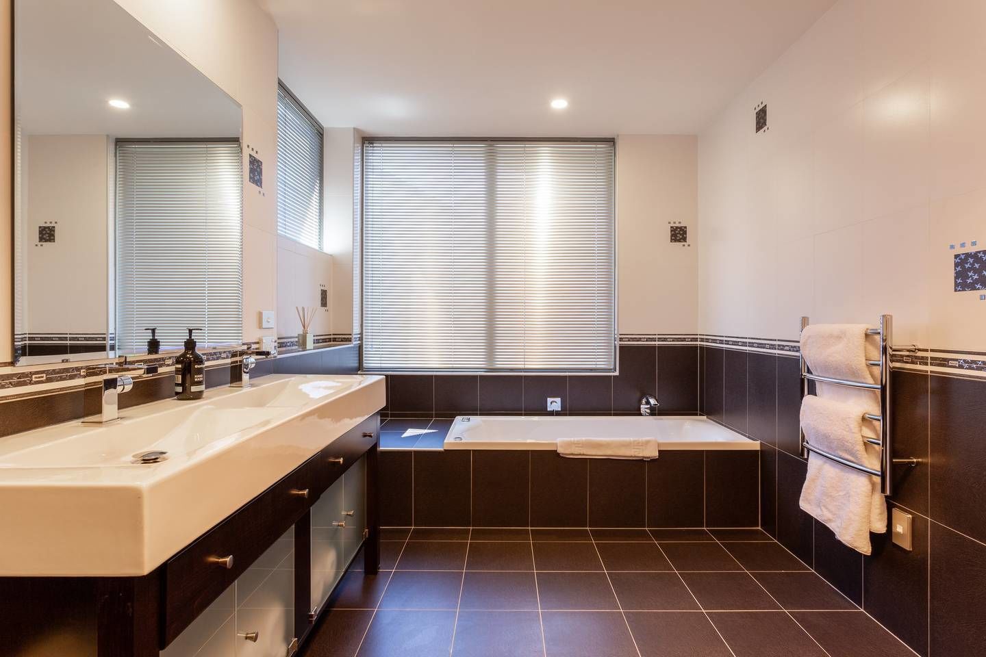 Une salle de bain moderne avec un meuble-lavabo à deux vasques, une baignoire et un grand miroir.