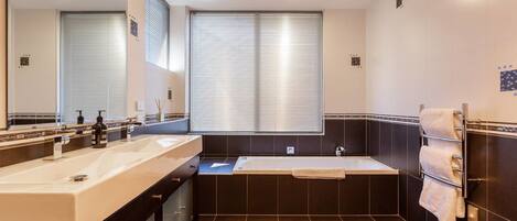 Une salle de bain moderne avec un meuble-lavabo à deux vasques, une baignoire et un grand miroir.