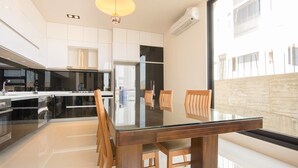 A modern kitchen with a glass dining table, wooden chairs, and a large window. - Simple Life Home Stay (Magong)