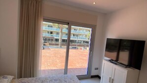 Una habitación de hotel con cama, televisor y puerta corrediza de vidrio que da a un espacio al aire libre.