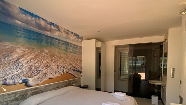 Una habitación de hotel con una cama grande, baño y vistas a la playa.