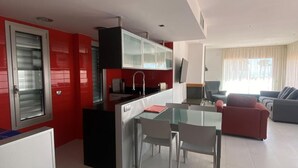 Una cocina moderna con comedor, pared de acento roja y un amplio ventanal.