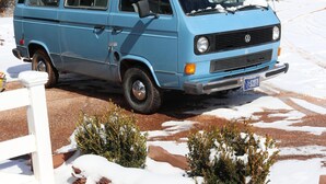 A blue van parked in a snowy driveway with a stone wall and small bushes in the foreground. -  Quiet and Solitude with Magnificent Patio View (Kanab)